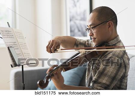Stock Photography - Korean musician playing violin in living room. Fotosearch