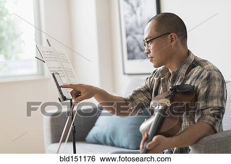 Stock Photograph - Korean musician using cell phone in living room. Fotosearch