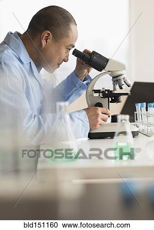 Stock Image - Korean scientist using microscope in laboratory. Fotosearch