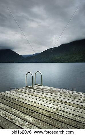 Stock Photograph - Ladder on wooden pier near still remote lake. Fotosearch