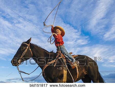 Stock Photo - Low angle view of Caucasian boy on horse throwing lasso. Fotosearch