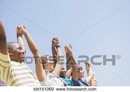 Low angle view of teenagers holding hands under blue sky View Large Photo Image Stock Photo - Low angle view of teenagers holding hands under blue sky. Fotosearch
