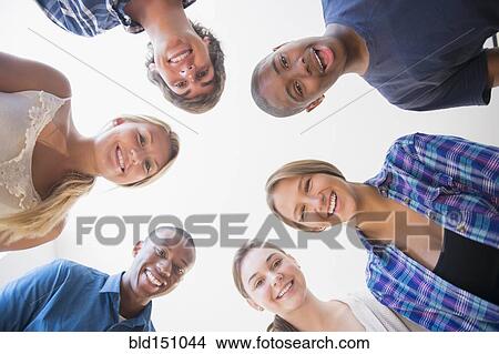 Picture - Low angle view of teenagers standing in circle. Fotosearch