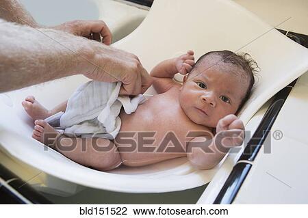 Stock Image - Man bathing mixed race baby. Fotosearch