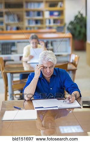 Man reading paperwork in library View Large Photo Image Stock Photo - Man reading paperwork in library. Fotosearch