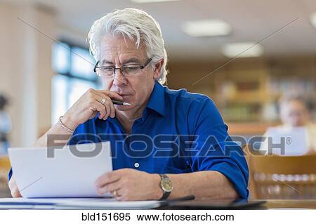 Man reading paperwork in library View Large Photo Image Stock Photography - Man reading paperwork in library. Fotosearch