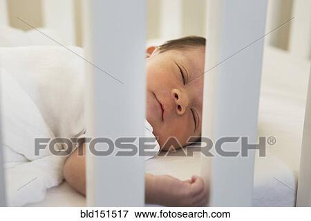 Stock Photo - Mixed race baby sleeping in crib. Fotosearch