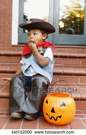Mixed race boy dressed as cowboy eating Halloween candy View Large Photo Image Stock Image - Mixed race boy dressed as cowboy eating Halloween candy. Fotosearch