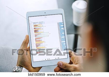 Stock Photo - Mixed race businessman examining graph on digital tablet. Fotosearch