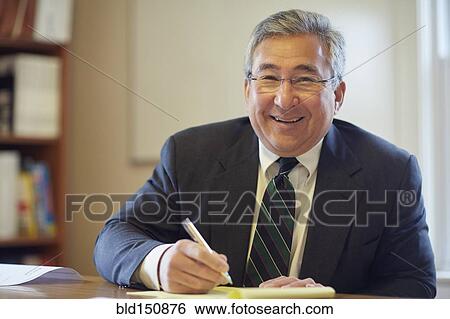 Mixed race businessman smiling at desk in office View Large Photo Image Stock Photograph - Mixed race businessman smiling at desk in office. Fotosearch
