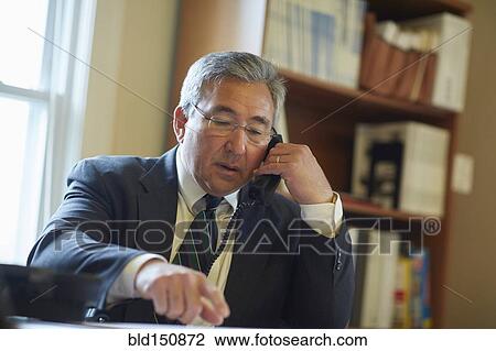 Mixed race businessman talking on telephone in office View Large Photo Image Stock Image - Mixed race businessman talking on telephone in office. Fotosearch