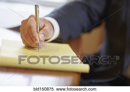 Stock Photography - Mixed race businessman writing on notepad at desk. Fotosearch