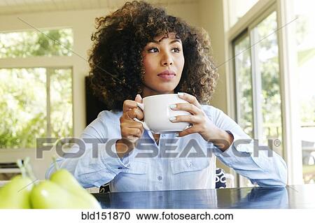 Mixed race businesswoman drinking coffee at table View Large Photo Image Stock Image - Mixed race businesswoman drinking coffee at table. Fotosearch