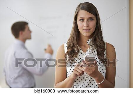 Stock Image - Mixed race businesswoman using cell phone in office. Fotosearch