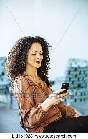 Stock Photo - Mixed race businesswoman using cell phone. Fotosearch