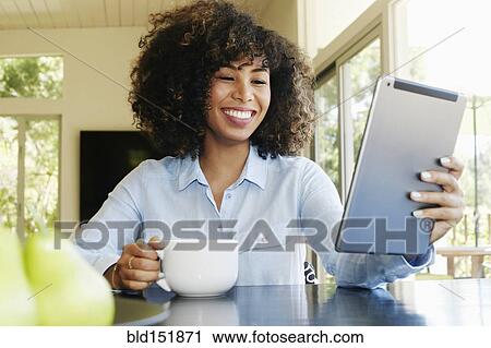 Mixed race businesswoman using digital tablet at table View Large Photo Image Stock Image - Mixed race businesswoman using digital tablet at table. Fotosearch
