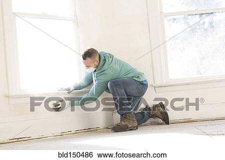 Stock Photograph - Mixed race carpenter cleaning wall. Fotosearch