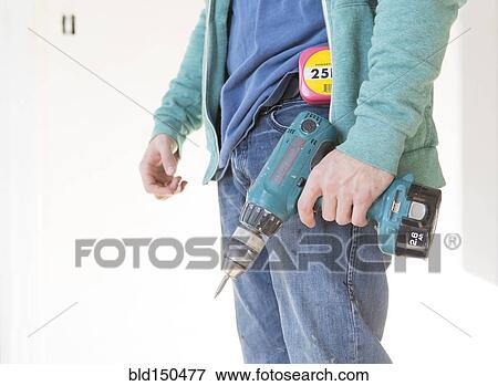 Stock Photo - Mixed race carpenter holding power drill. Fotosearch