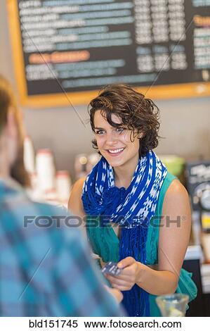 Stock Photography - Mixed race cashier talking to customer in cafe. Fotosearch