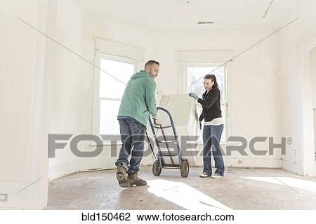 Stock Image - Mixed race couple moving into new home. Fotosearch