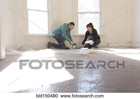 Stock Image - Mixed race couple painting walls of new home. Fotosearch
