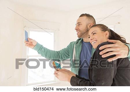 Mixed race couple selecting color swatches in new home View Large Photo Image Picture - Mixed race couple selecting color swatches in new home. Fotosearch