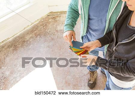 Stock Image - Mixed race couple selecting color swatches in new home. Fotosearch