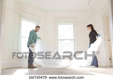 Mixed race couple spreading tarp in new home View Large Photo Image Stock Photo - Mixed race couple spreading tarp in new home. Fotosearch