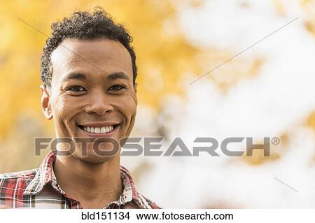 Picture - Mixed race man smiling outdoors. Fotosearch