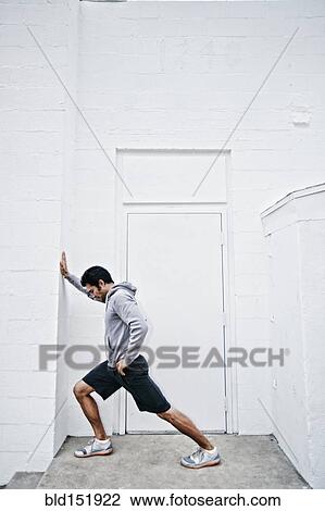 Stock Image - Mixed race man stretching in doorway. Fotosearch