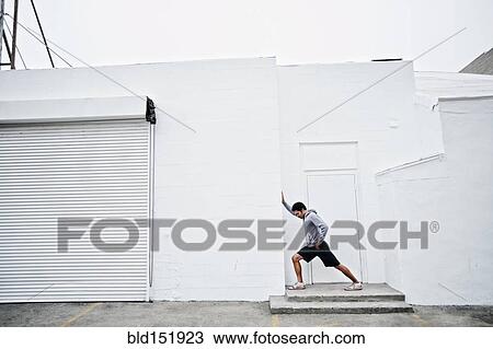 Stock Image - Mixed race man stretching in doorway. Fotosearch