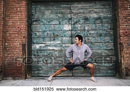 Stock Photography - Mixed race man stretching near industrial building. Fotosearch