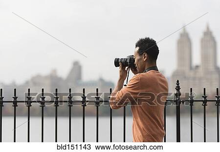 Mixed race man taking photograph on urban waterfront View Large Photo Image Stock Image - Mixed race man taking photograph on urban waterfront. Fotosearch