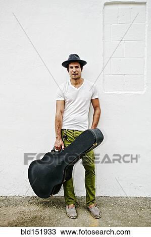 Stock Image - Mixed race musician carrying guitar case. Fotosearch