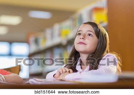 Picture - Mixed race student sitting at desk in library. Fotosearch
