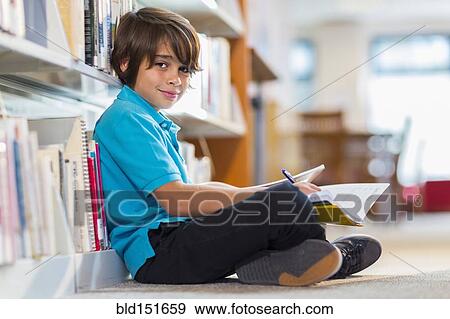 Stock Photo - Mixed race student writing in notepad on floor in library. Fotosearch