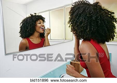 Mixed race woman applying makeup in mirror View Large Photo Image Stock Photograph - Mixed race woman applying makeup in mirror. Fotosearch