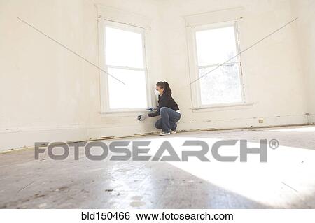 Stock Photograph - Mixed race woman cleaning wall in new home. Fotosearch