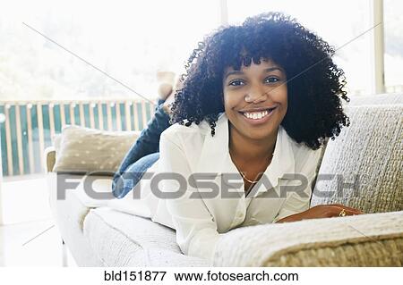 Stock Photo - Mixed race woman laying on sofa. Fotosearch