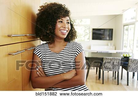 Stock Image - Mixed race woman leaning on cabinet. Fotosearch