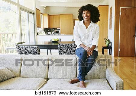 Stock Photo - Mixed race woman sitting on sofa. Fotosearch