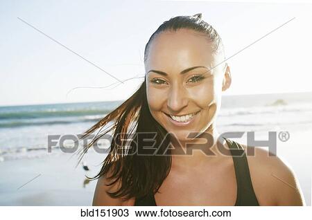 Stock Image - Mixed race woman smiling on beach. Fotosearch
