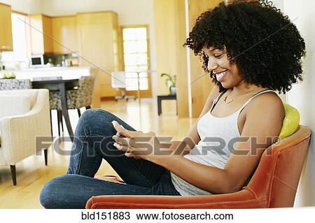 Mixed race woman using cell phone in armchair View Large Photo Image Stock Image - Mixed race woman using cell phone in armchair. Fotosearch