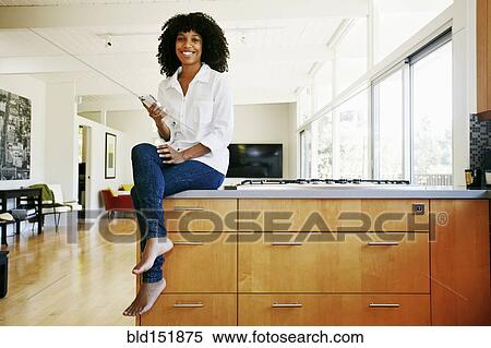 Mixed race woman using cell phone in domestic kitchen View Large Photo Image Stock Photography - Mixed race woman using cell phone in domestic kitchen. Fotosearch