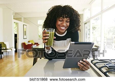 Mixed race woman using digital tablet in domestic kitchen View Large Photo Image Stock Photo - Mixed race woman using digital tablet in domestic kitchen. Fotosearch