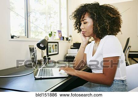 Mixed race woman using laptop at desk View Large Photo Image Stock Photograph - Mixed race woman using laptop at desk. Fotosearch