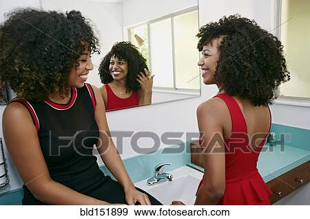 Stock Photo - Mixed race women smiling in mirror. Fotosearch