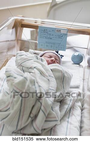Stock Photography - Mixed race wrapped in blanket in hospital crib. Fotosearch