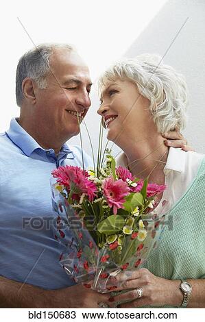 Older couple holding bouquet of flowers View Large Photo Image Stock Image - Older couple holding bouquet of flowers. Fotosearch
