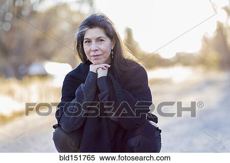 Stock Photography - Older Hispanic woman crouching outdoors. Fotosearch